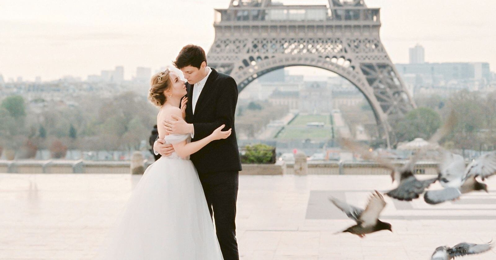 Mariés posant devant la tour Eiffel à Paris