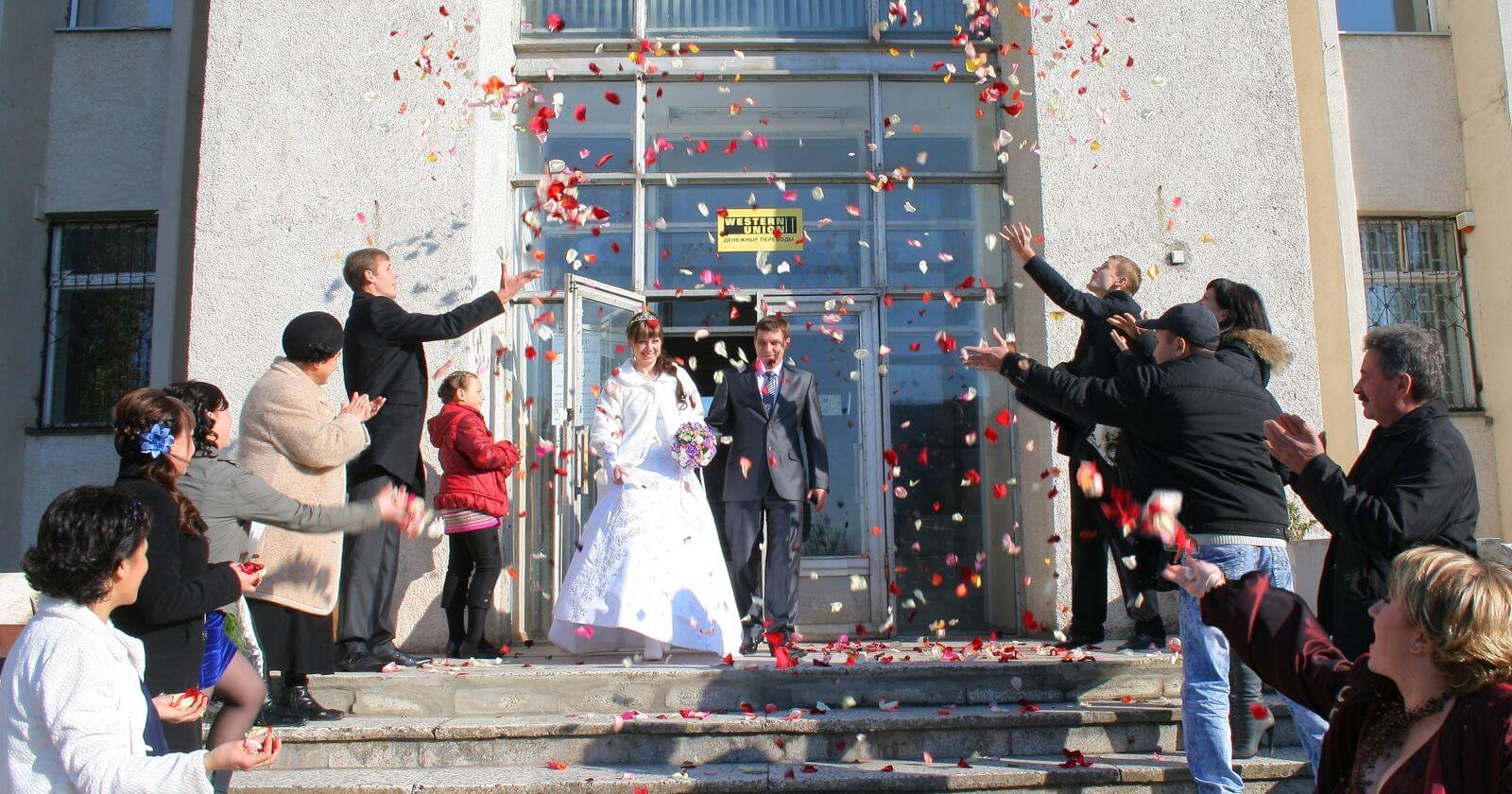 Mariés qui sortent du bâtiment sous les confettis
